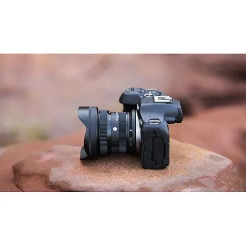 A modern mirrorless camera with a wide angle lens resting on a rock
