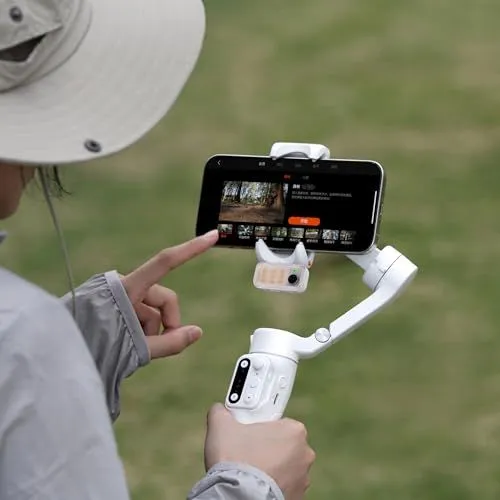 A person using a white smartphone gimbal stabilizer outdoors