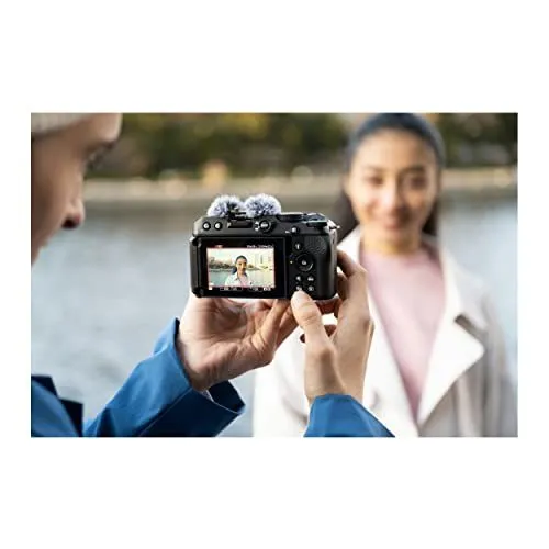 A photographer filming a woman outdoors with a compact camera