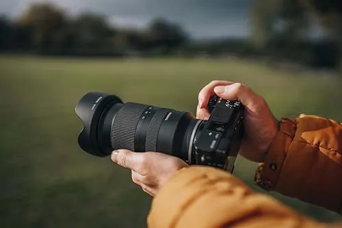 A photographer holding a professional camera in an outdoor setting
