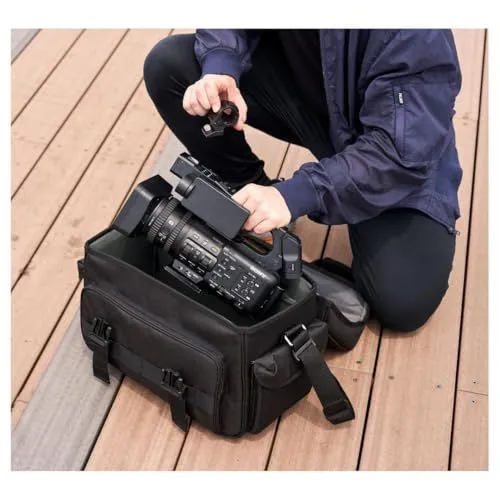 A professional camera being placed into a black padded gear bag