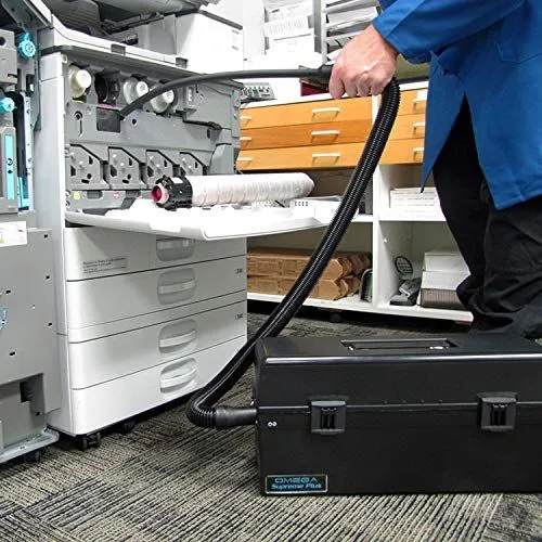 A professional technician cleaning a large office copier with a specialized vacuum.