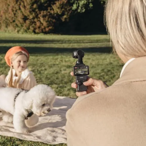 A woman filming a child and dog with a handheld gimbal camera