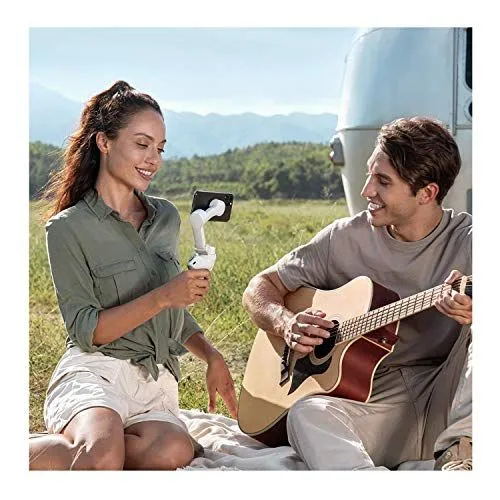 A woman filming a man playing guitar outdoors