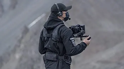 Filmmaker operating professional camera gear in rugged terrain